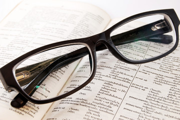 closeup of old dictionary and glasses