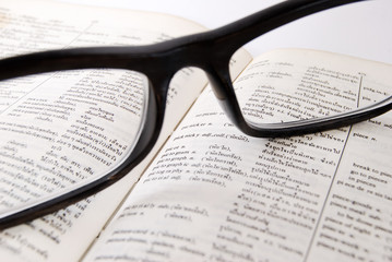 closeup of old dictionary and glasses