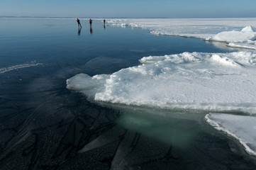 Three scandinavian ice skaters on a large frozen lake