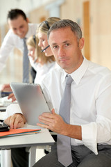 Office worker looking at internet on electronic pad