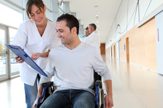 Beautiful nurse standing by man in wheelchair