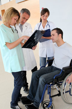 Medical team with handicapped person looking at X-ray