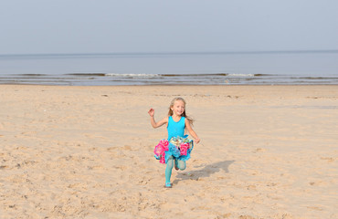 Little and joyful girl running on a beach
