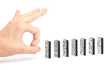 Hand ready to push dominoes in a line to cause chain reaction