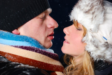 attractive young couple is kissing at winter evening