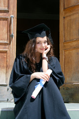 Young caucasian smiling student in gown near the university