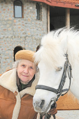 smiling elderly woman near white pony