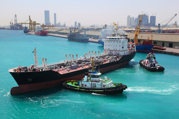 boats docked to industrial ship in port sail to sea at sunny day