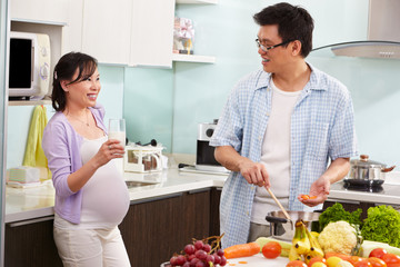 Obraz na płótnie Canvas Pregnant wife drinking milk watching her husband