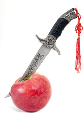 Dagger in  ripe apple on a white background