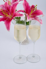 Two glasses of champagne and pink lily