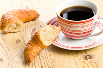 breaking croissant with coffee