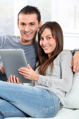 Couple sitting on sofa with electronic pad