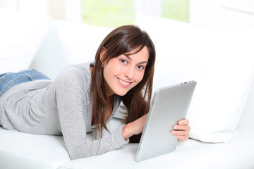 Young woman sitting on sofa with electronic pad