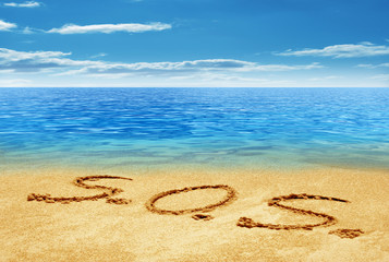 S.O.S. handwritten in sand on a beach