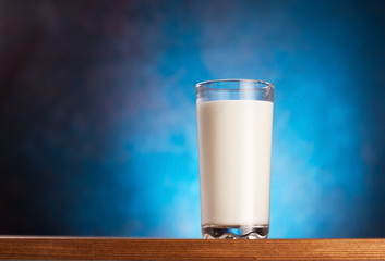 Full glass of milk on wooden table.