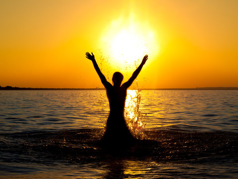 catching sun - Swimmer jumping out of sea water on golden sunset