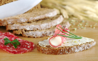 Salami and cream cheese with chives on brown bread