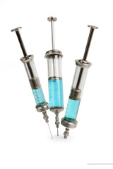 Old glass medical syringes are thrust in a white surface and iso