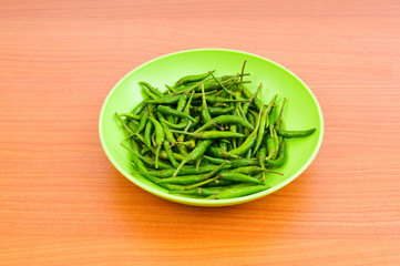 Hot peppers in the plate on wooden table
