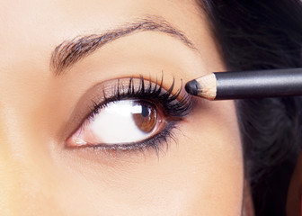 Eye close-up of model applying black kohl eyeliner eye makeup