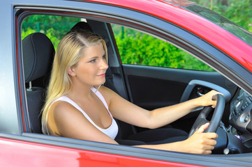 Fototapeta na wymiar beautiful woman driver in red shiny car outdoors smiling