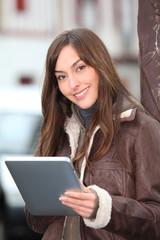 Fototapeta premium Young woman using electronic pad in town