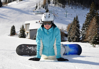 Fototapeta na wymiar Young girl relaxing on ski slope with snowboard