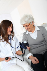 Closeup of nurse checking senior woman blood pressure