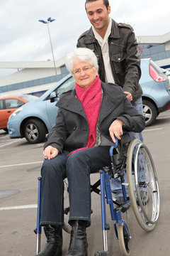 Young man assisting senior woman in wheelchair