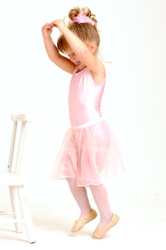 Little smiley girl wearing a pink ballet outfit dancing