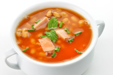 bean soup with ham and tomatoes in a white soup cup