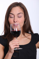 Beautiful woman in black dress tasting red wine