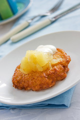 Potato latke topped with apple sauce and white sour cream