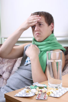 sick man with tablets ans glass of water