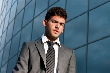 Young businessman looking to camera on modern building