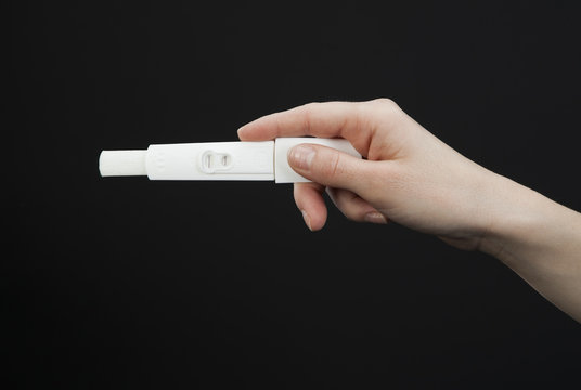 main de femme tenant un test de grossesse positif