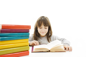 Young girl sitting at the desk and reading book.