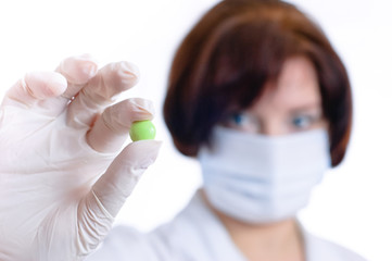 Doctor looking at green round pill