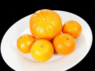 Orange fruits on white plate, towards dark background