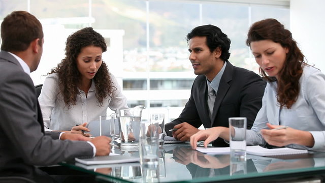 Four businesspeople talking at a table during a meeting