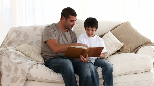 Happy dad and son looking at a photo album on the sofa