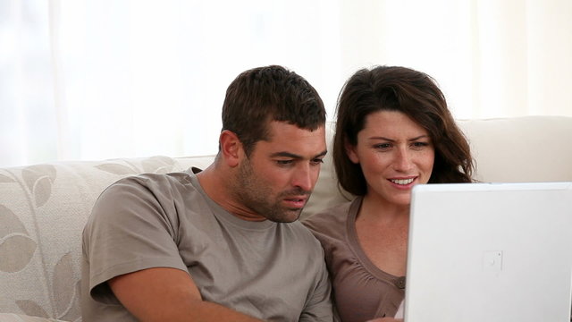 Surprised couple surfing on the web together at home