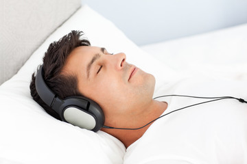Man sleeping with headphones lying on his bed at home