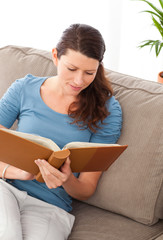 Attentive woman looking at a photo album sitting on her sofa