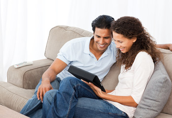Obraz premium Lovely couple watching videos together sitting on their sofa