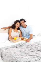 Obraz na płótnie Canvas Portrait of a cute couple having breakfast in their bed