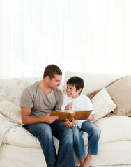 Adorable boy looking at a photo album with his father