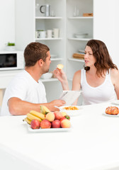 Cute woman giving bread to his husband during breakfast in the k