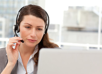 Concentrated businesswoman working on her laptop while calling